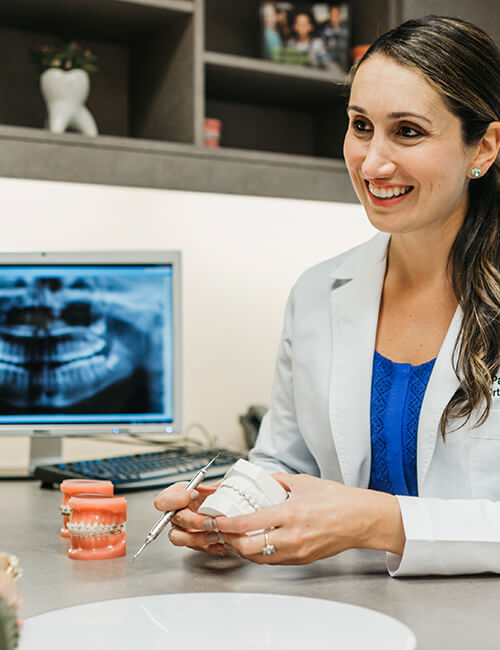 DrPatraAlatsisshowingpatientacustomteethmodel Gig Harbor Orthodontics